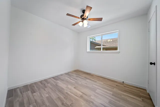 an empty room with a window and a ceiling fan