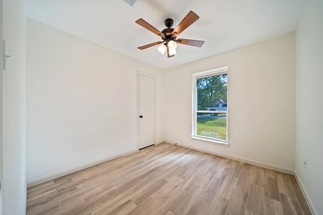 an empty room with wooden floor and ceiling fan