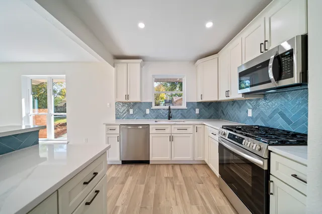 a kitchen with stainless steel appliances granite countertop a stove a sink and a microwave