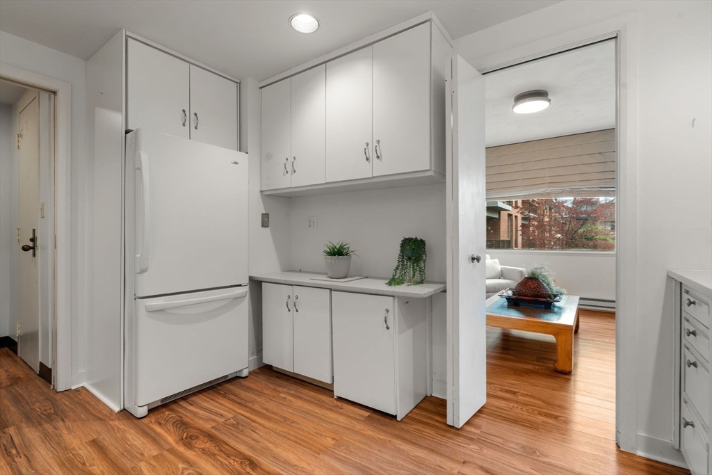 75 Grove Street, Unit 227 Wellesley, MA 02482 - Photo 15 of 29 a kitchen with white cabinets and wooden floor