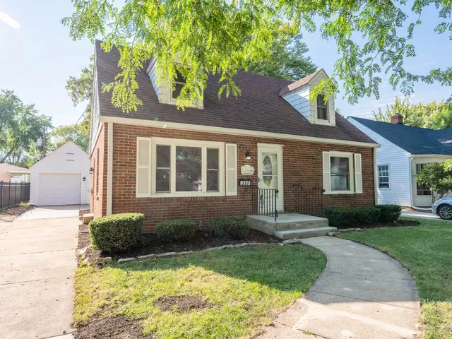 a front view of a house with garden and trees