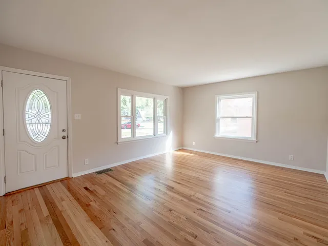 an empty room with wooden floor and window