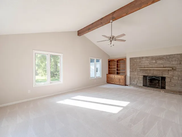 an empty room with windows and fireplace