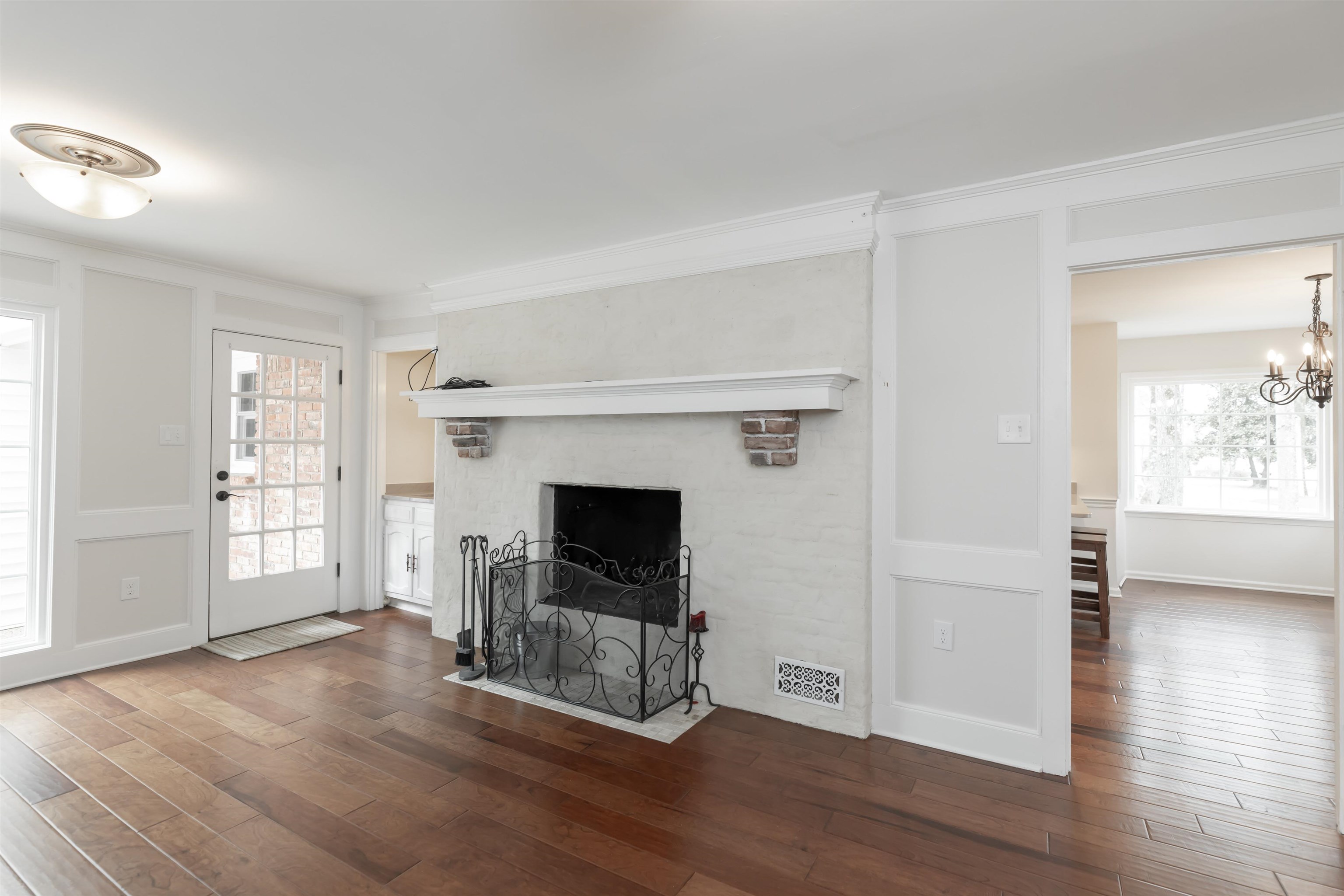 8441 Dogwood Road Germantown, TN 38139 - Photo 8 of 29 Unfurnished living room with dark wood-style flooring, a decorative wall, a fireplace with flush hearth, crown molding, and suspended lighting