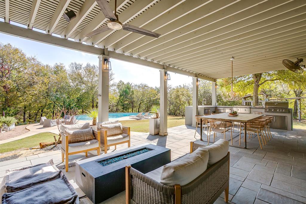 357 Wood Lake Road Aledo, TX 76008 - Photo 28 of 40 a view of a patio with a dining table and chairs under an umbrella