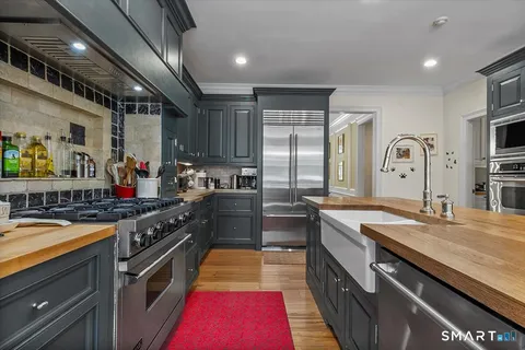 a large kitchen with stainless steel appliances granite countertop a stove a sink dishwasher and refrigerator with wooden floor