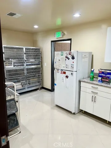 a view of kitchen with refrigerator and white cabinets