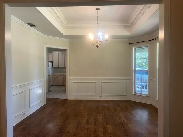 an empty room with wooden floor cabinet and windows