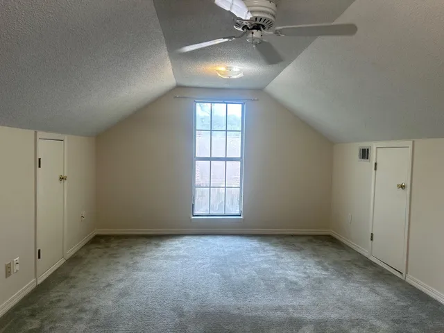 an empty room with windows and fan