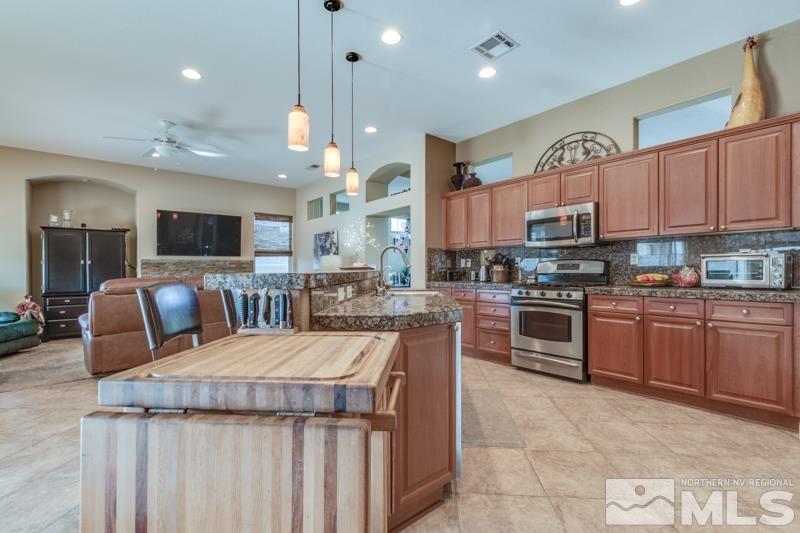 1696 Ghettis Way Reno, NV 89521 - Photo 11 of 25 a kitchen with stainless steel appliances kitchen island granite countertop a stove top oven a sink dishwasher a dining table and chairs
