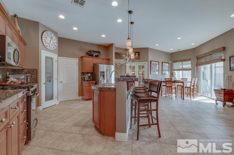 1696 Ghettis Way Reno, NV 89521 - Photo 10 of 25 a kitchen with stainless steel appliances kitchen island granite countertop a table chairs and a view of living room
