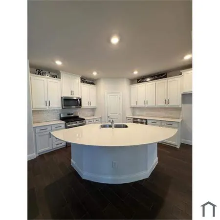 a view of a kitchen with kitchen island a sink wooden floor and a refrigerator