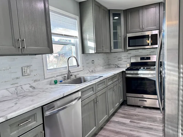 a kitchen with granite countertop a sink stainless steel appliances and cabinets