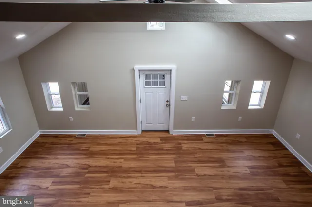 a view of an empty room with window and wooden floor