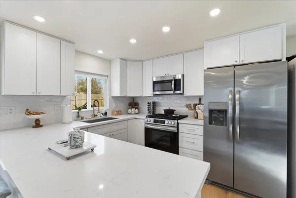 a kitchen with a refrigerator a microwave a sink and cabinets