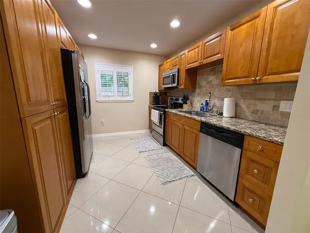 a kitchen with stainless steel appliances granite countertop a refrigerator a sink a stove a microwave a sink and dishwasher