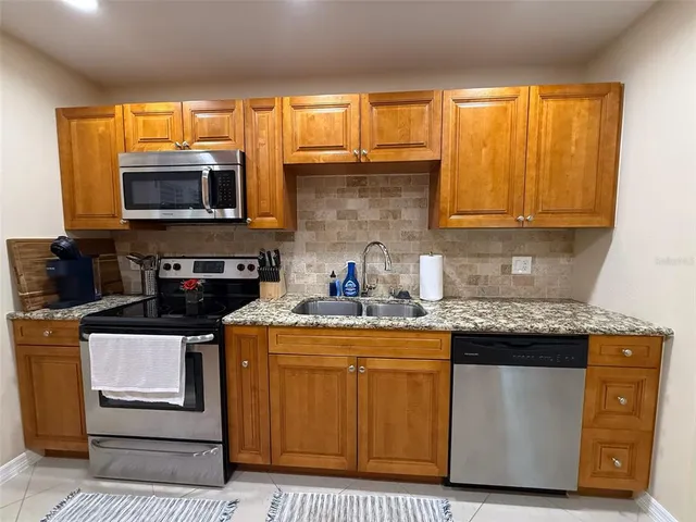 a kitchen with stainless steel appliances granite countertop a stove a sink and a microwave