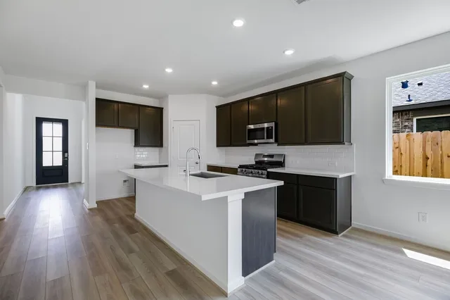 a kitchen with a sink a counter top space stainless steel appliances and a window