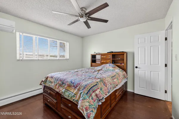 a bedroom with a bed dresser and wooden floor