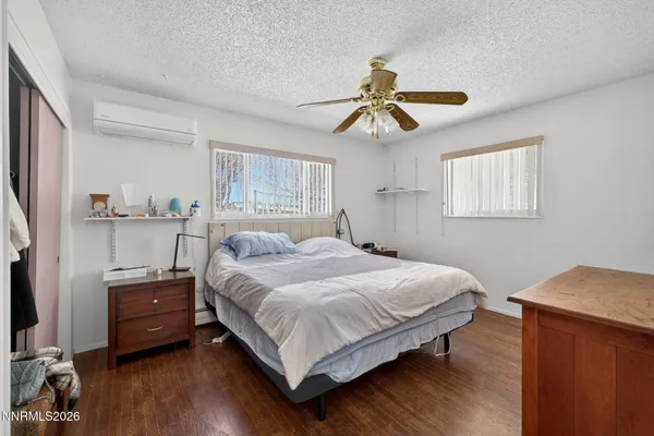 a bedroom with a bed a dresser and wooden floor