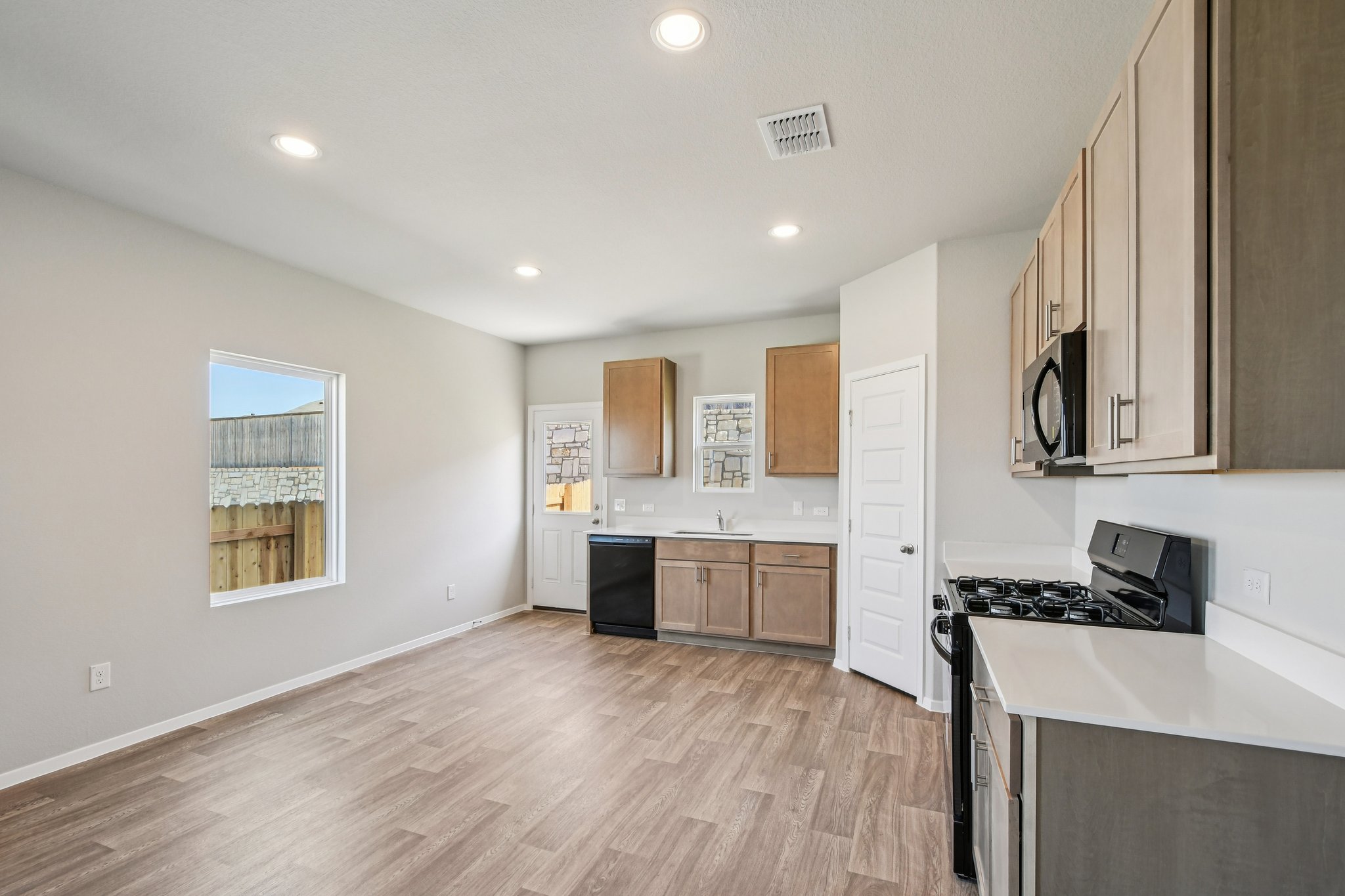 11913 Ellena Cove Austin, TX 78747 - Photo 8 of 35 a large kitchen with stainless steel appliances granite countertop a stove a sink dishwasher and a refrigerator with wooden floor