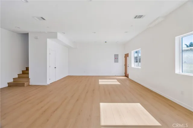 an empty room with wooden floor and a hallway