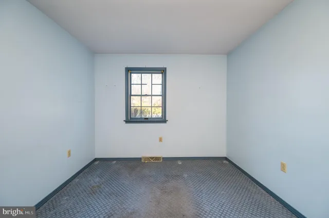 a view of an empty room with window and hardwood floor