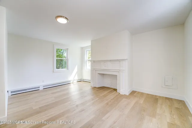 an empty room with windows and fireplace