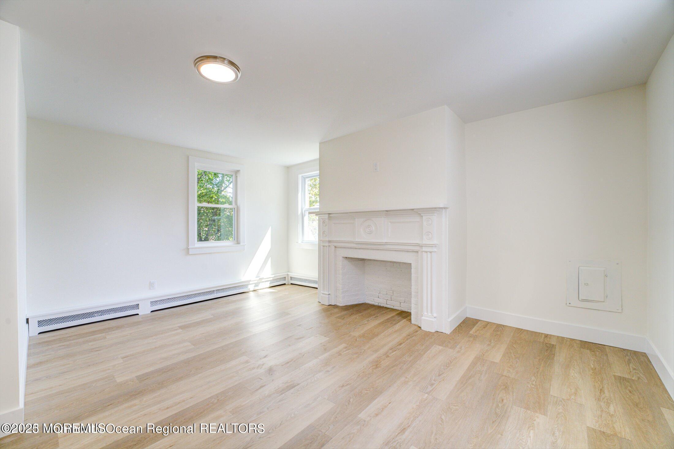 54 Main Street, Unit 2 Keyport, NJ 07735 - Photo 4 of 25 an empty room with windows and fireplace