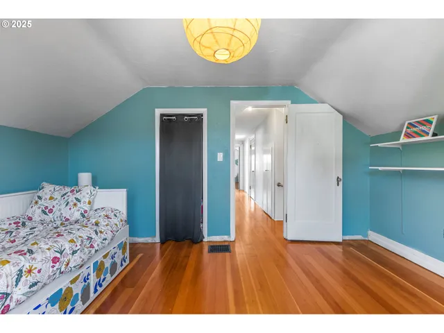 a view of a bedroom with wooden floor and window