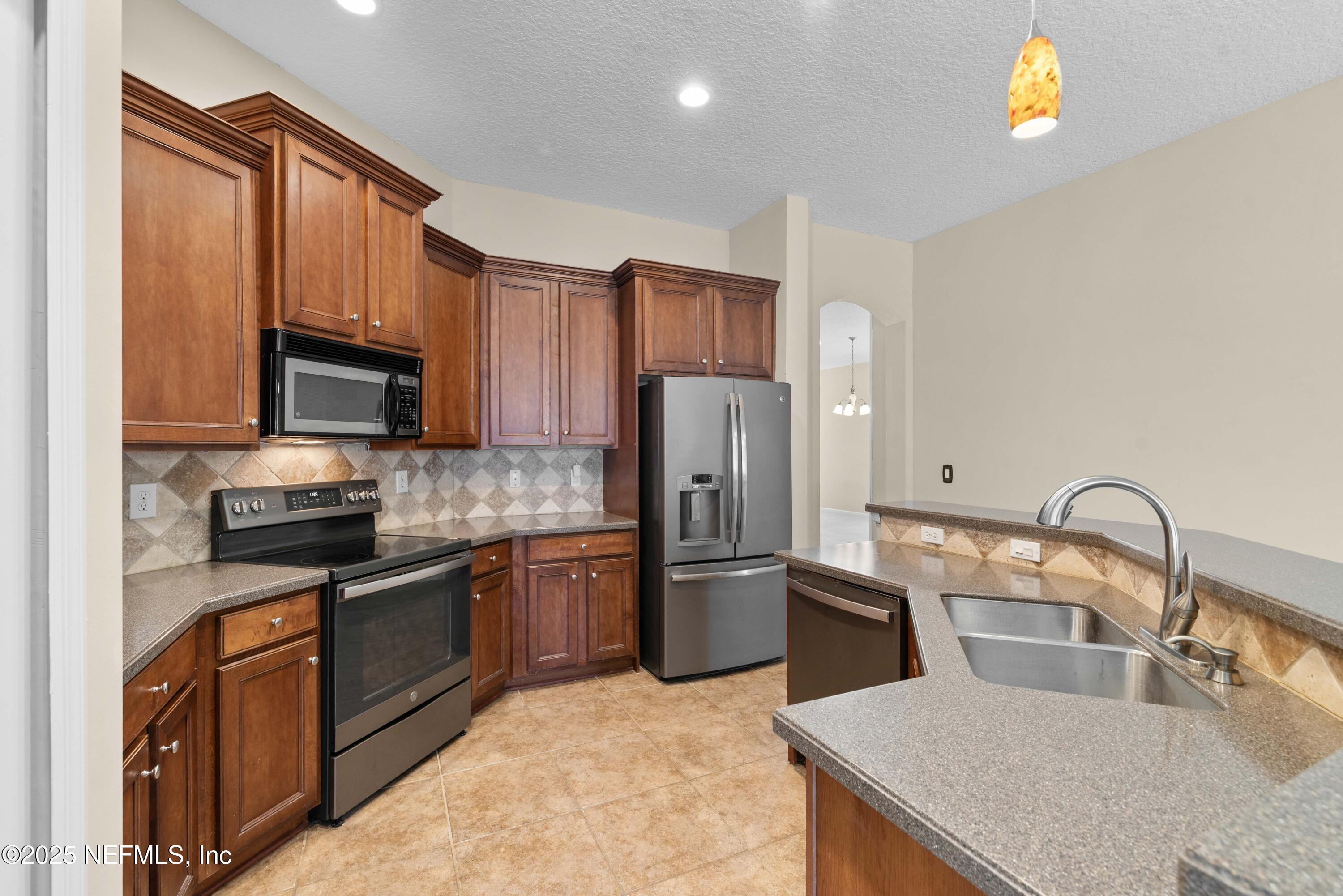 11798 Blueberry Lane Macclenny, FL 32063 - Photo 8 of 30 a kitchen with stainless steel appliances granite countertop a refrigerator a stove top oven a sink and dishwasher