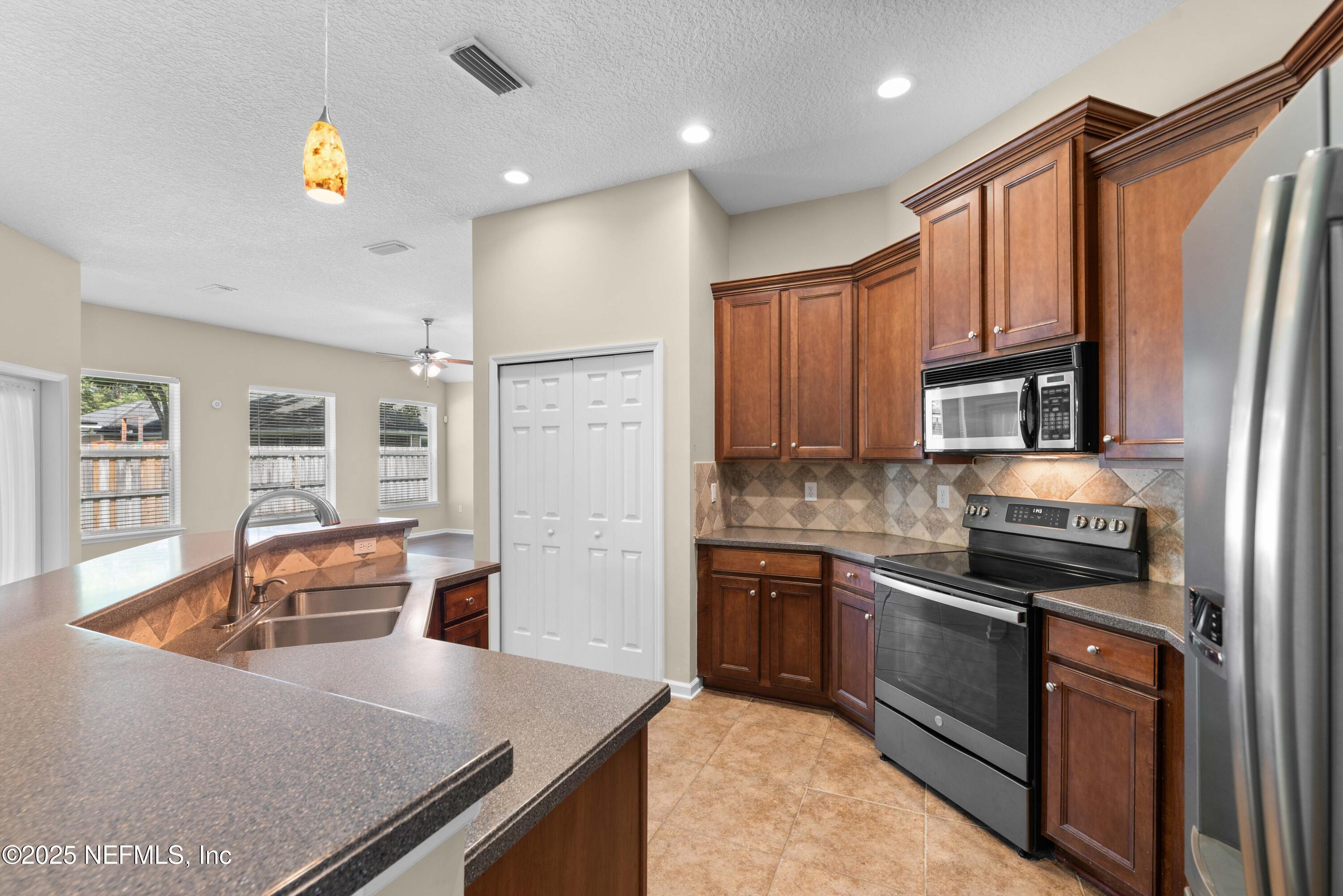 11798 Blueberry Lane Macclenny, FL 32063 - Photo 9 of 30 a kitchen with stainless steel appliances granite countertop a refrigerator a stove top oven a sink dishwasher and wooden cabinets