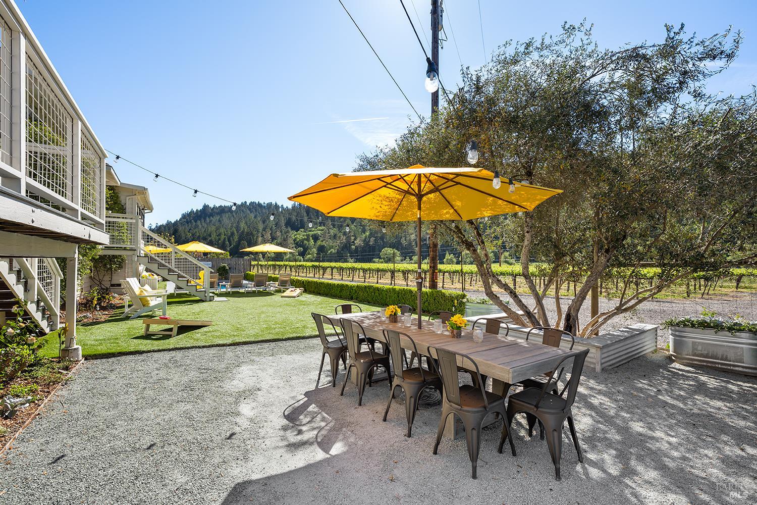 16530 Laughlin Road Guerneville, CA 95446 - Photo 41 of 57 Outdoor dining area with vineyard backdrop and string lighting