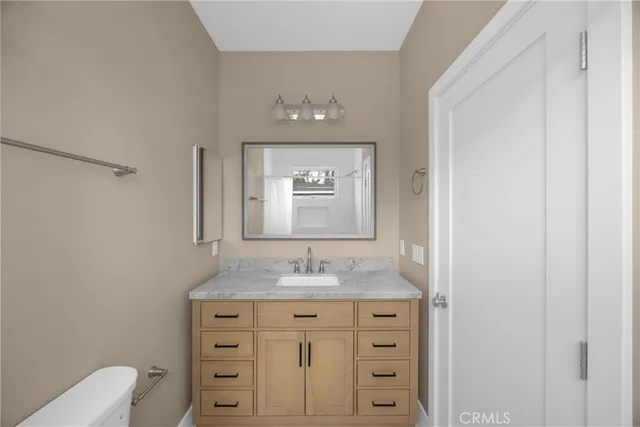 a bathroom with a granite countertop sink toilet and mirror