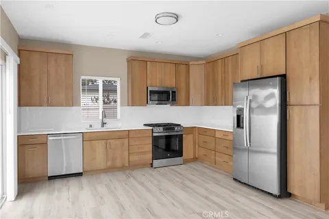 a kitchen with stainless steel appliances granite countertop white cabinets a refrigerator a sink a stove a microwave and wooden floors