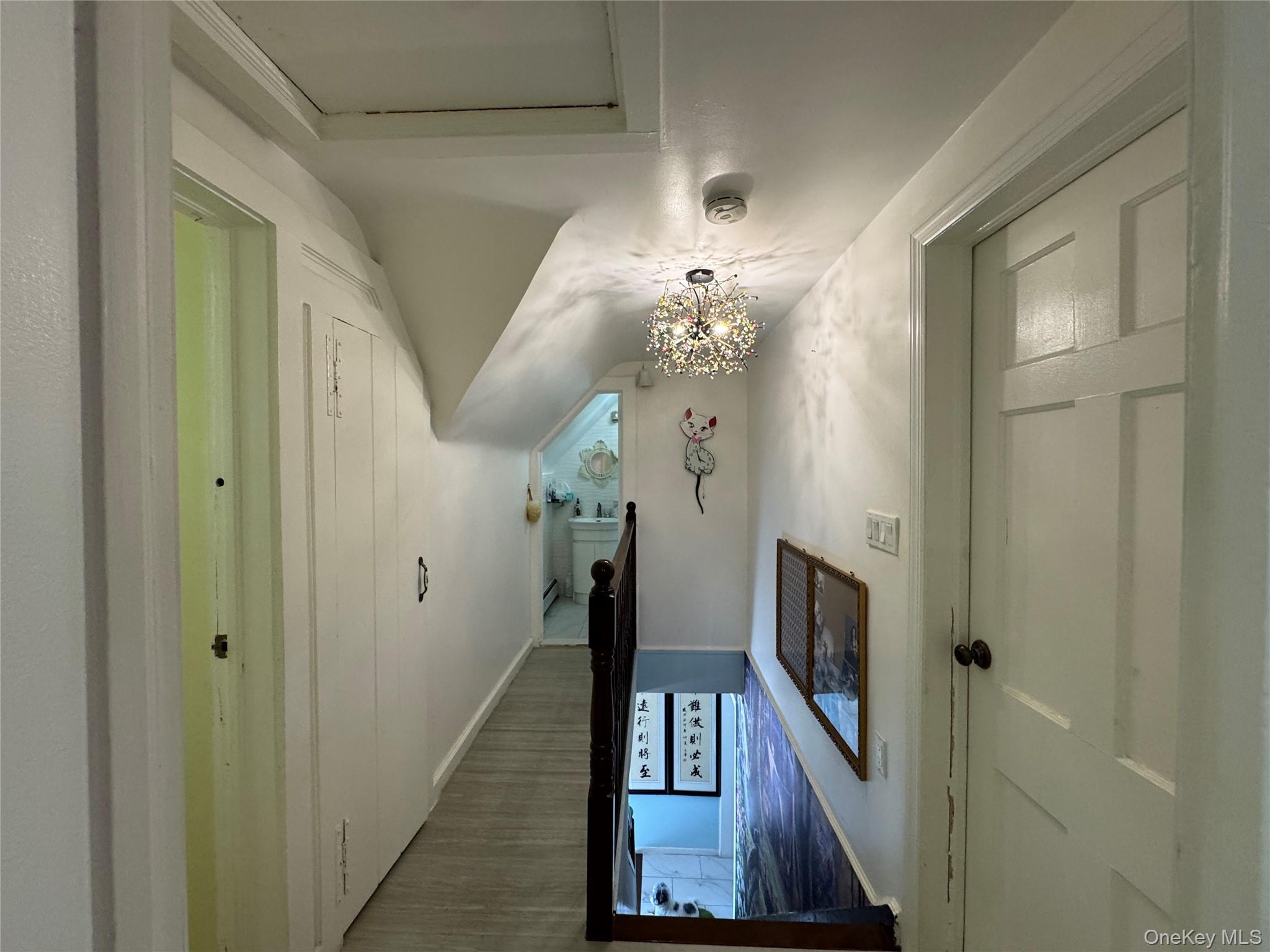 16 Ascot Ridge Great Neck, NY 11021 - Photo 22 of 23 Corridor featuring a chandelier, lofted ceiling, an upstairs landing, and wood finished floors