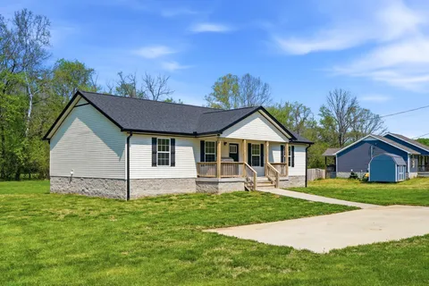 a front view of a house with a yard and trees