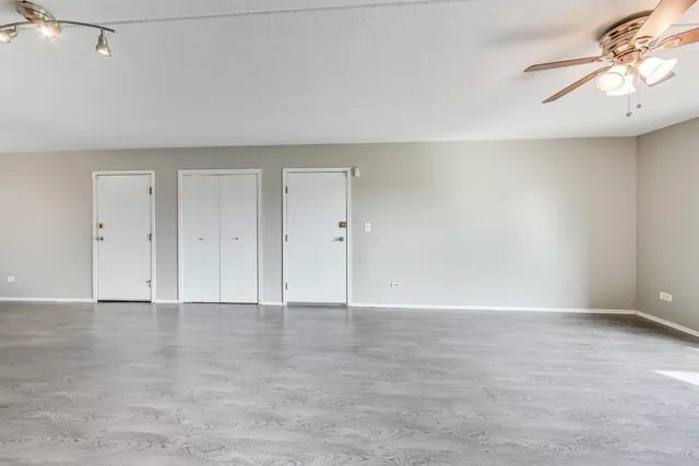 a view of a livingroom with a ceiling fan & windows