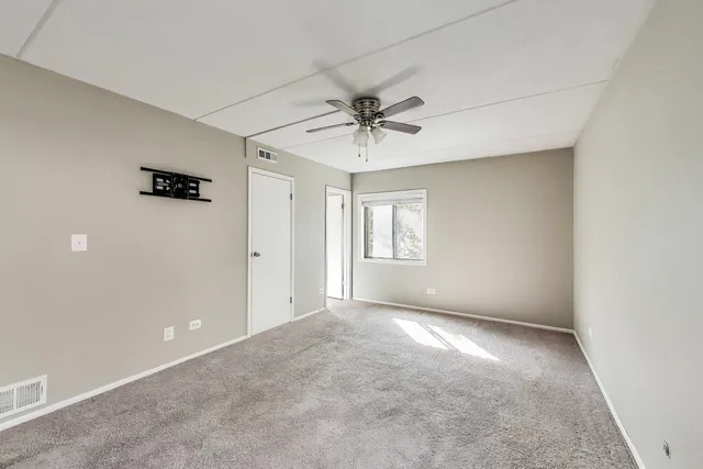 an empty room with windows and ceiling fan