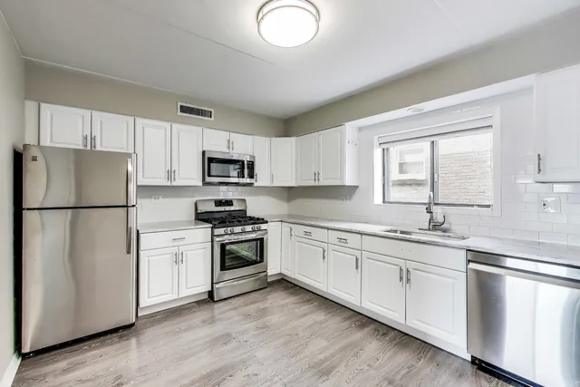 a kitchen with white cabinets and stainless steel appliances