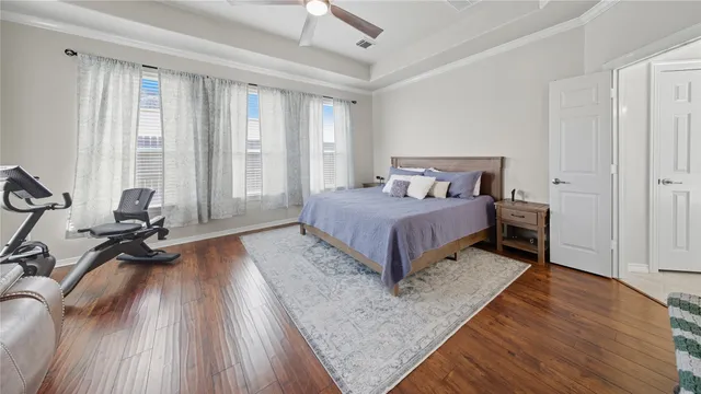 a bedroom with a bed a large window and walk in closet with wooden floor