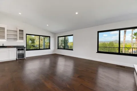 a view of an empty room with wooden floor and windows