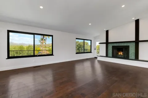 a view of an empty room with a fireplace and wooden floor