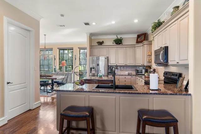 a kitchen with stainless steel appliances granite countertop a refrigerator a stove a sink dishwasher and white cabinets with wooden floor