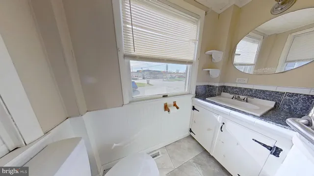 a bathroom with a granite countertop sink and a mirror next to a window
