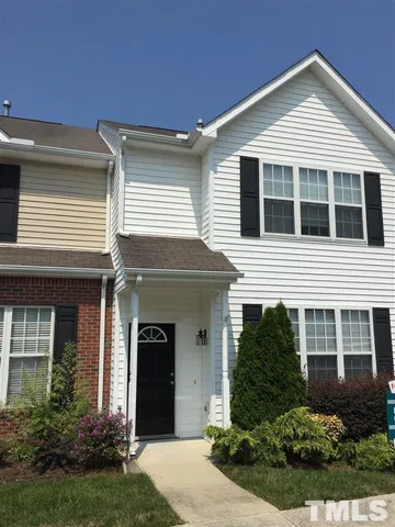 a view of a house with potted plants and a yard