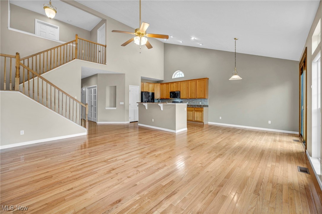143 Stone Ridge Way Berea, OH 44017 - Photo 19 of 47 Unfurnished living room featuring high vaulted ceiling, light wood-type flooring, a ceiling fan, and stairway