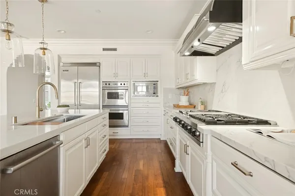 a white kitchen with granite countertop white cabinets and a granite counter tops with a wooden floor