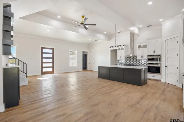 a large kitchen with stainless steel appliances kitchen island a large counter top and wooden floors