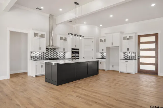 a kitchen with stainless steel appliances kitchen island granite countertop a stove a refrigerator and a wooden floors